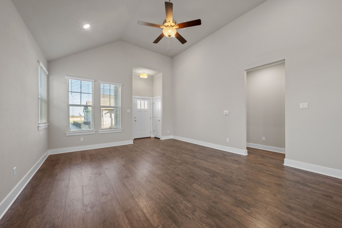 217 Pinnacle Lane Kyle, TX 78640 - Photo 5 of 33 an empty room with wooden floor chandelier fan and windows