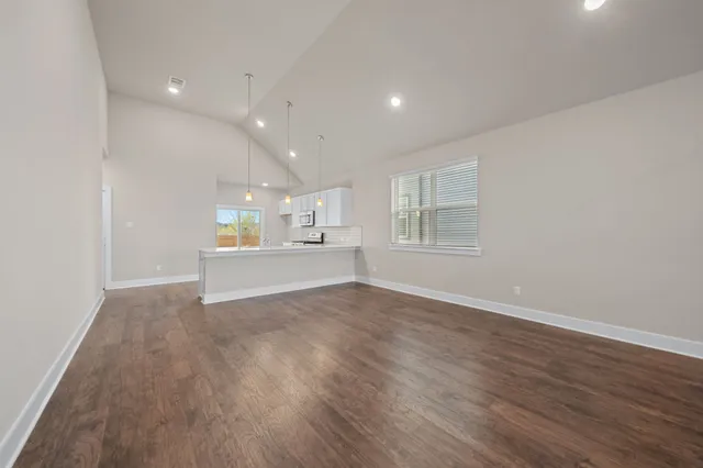 a view of an empty room with a window and wooden floor