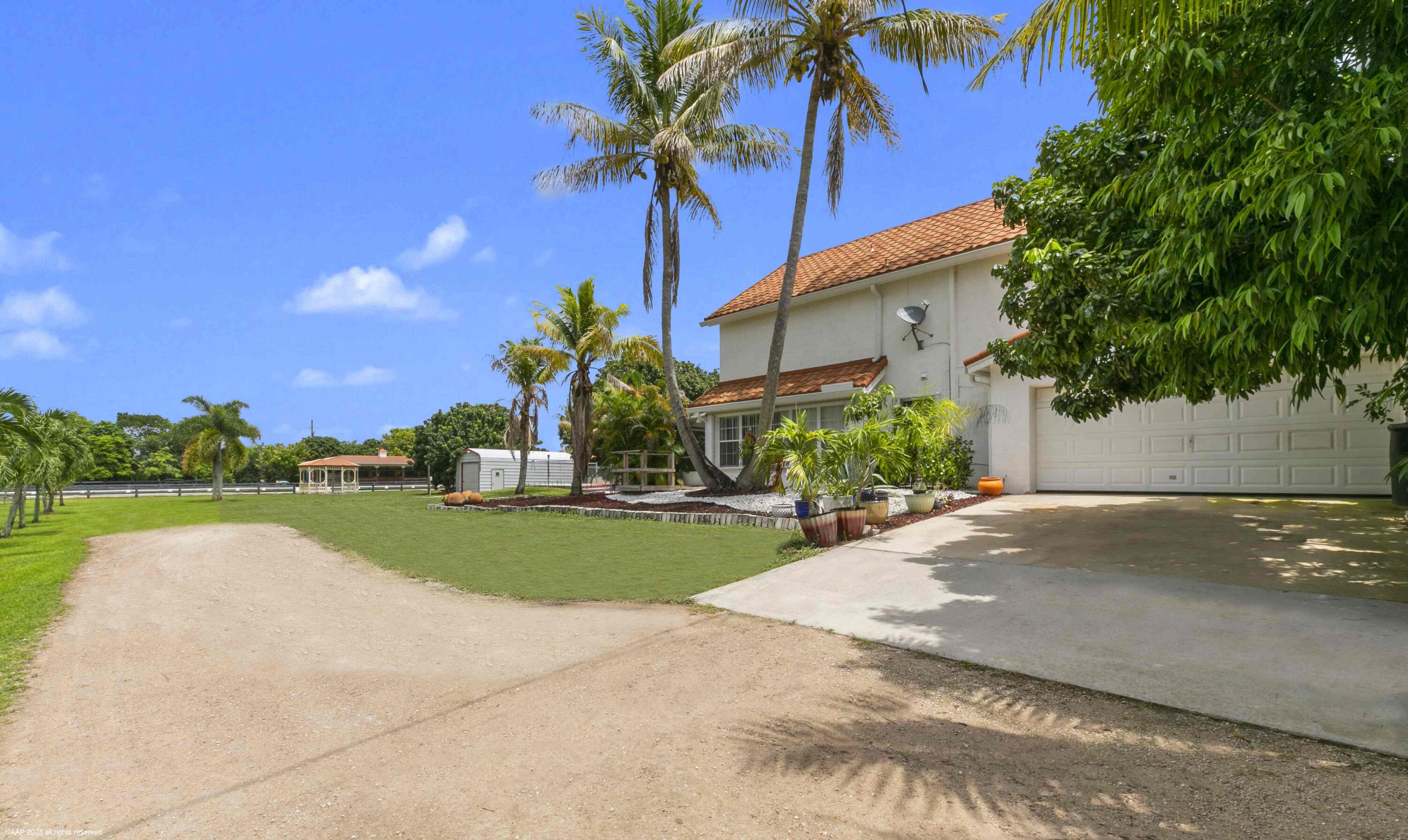 16559 Rustic Road Wellington, FL 33470 - Photo 42 of 82 a view of a house with a yard and palm trees
