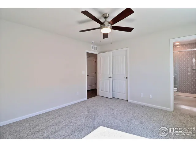 an empty room with ceiling fan and windows