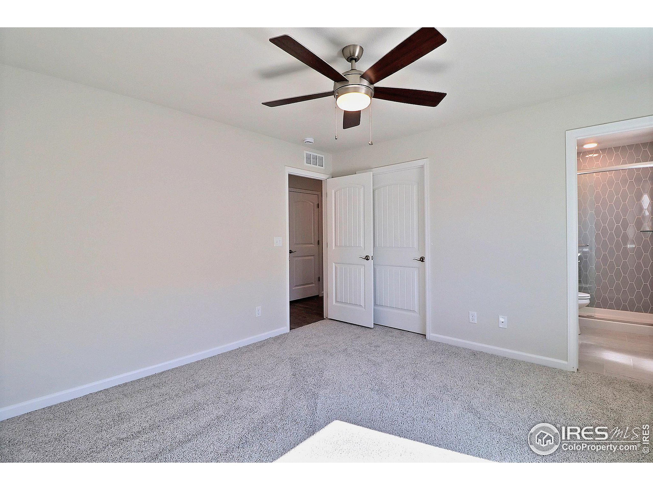 4301 Rockcress Road Evans, CO 80620 - Photo 18 of 26 an empty room with ceiling fan and windows