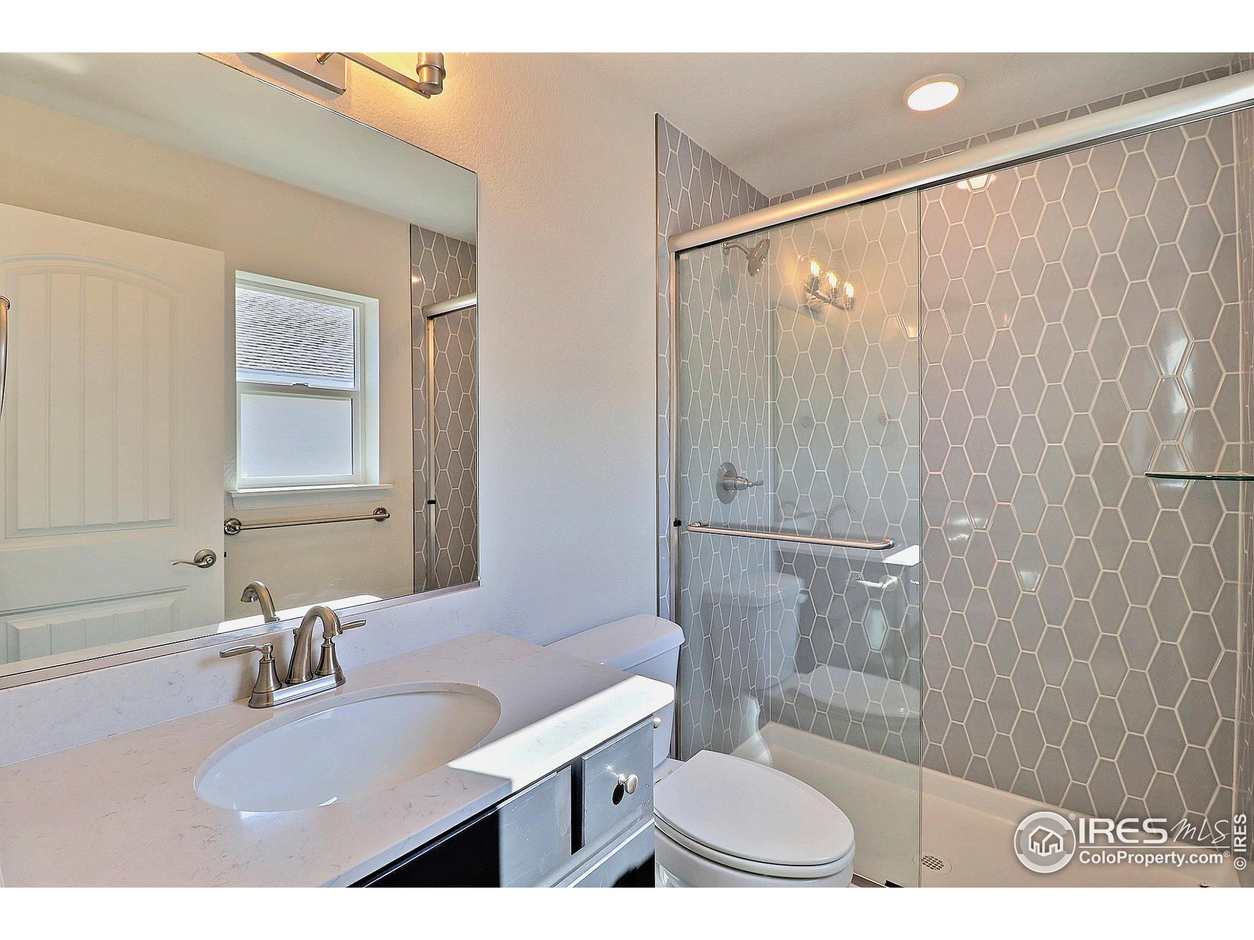 4301 Rockcress Road Evans, CO 80620 - Photo 20 of 26 a bathroom with a sink toilet a mirror and shower