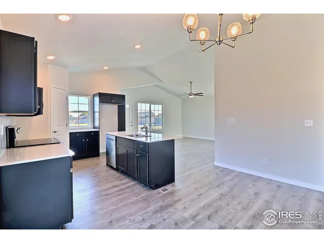 a kitchen with stainless steel appliances granite countertop a refrigerator a sink dishwasher a stove and a dining table with wooden floor