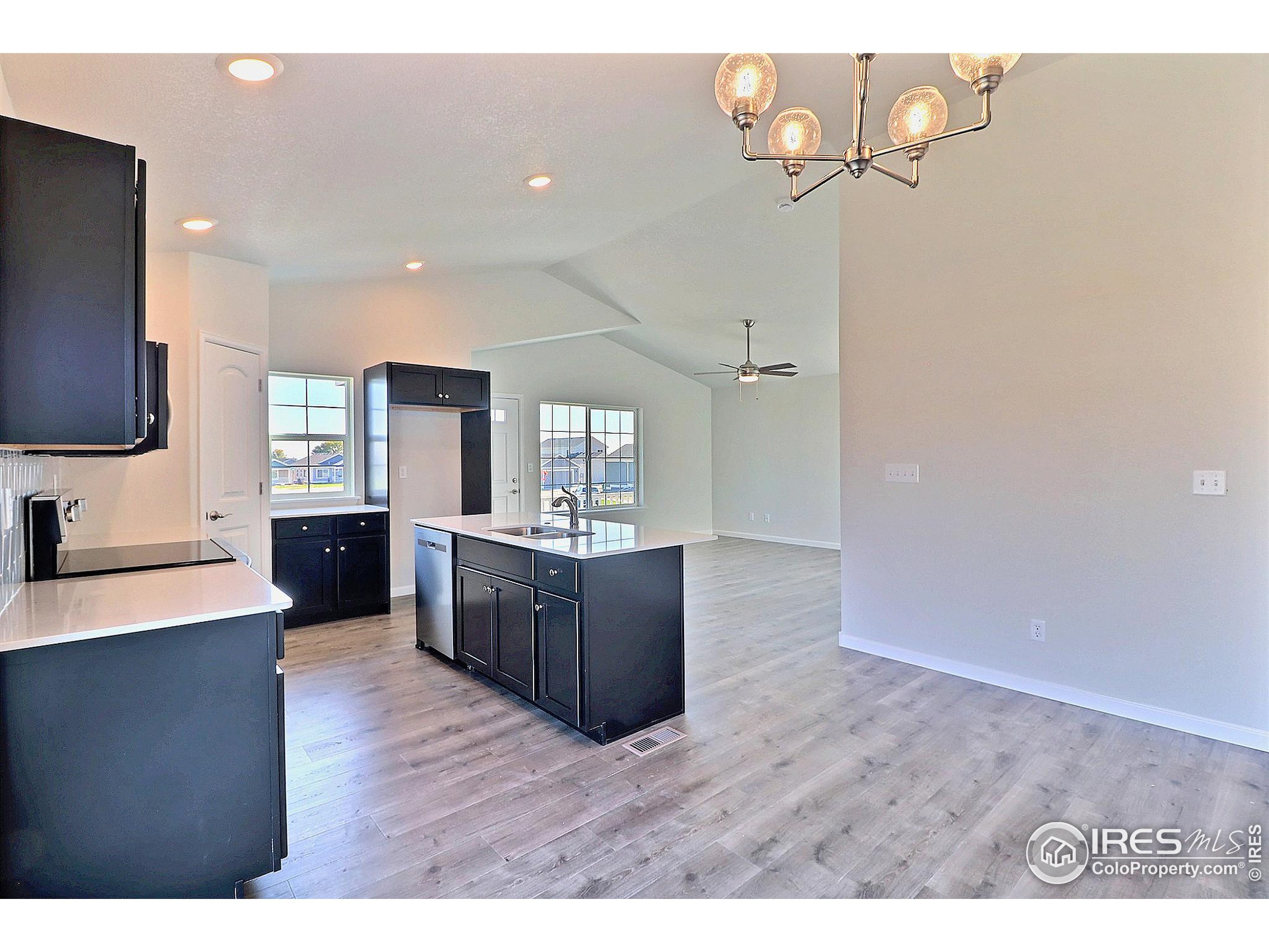 4301 Rockcress Road Evans, CO 80620 - Photo 10 of 26 a kitchen with stainless steel appliances granite countertop a refrigerator a sink dishwasher a stove and a dining table with wooden floor