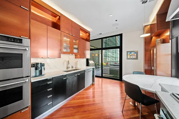 a large kitchen with stainless steel appliances granite countertop a stove top oven a sink dishwasher a dining table and chairs with wooden floor