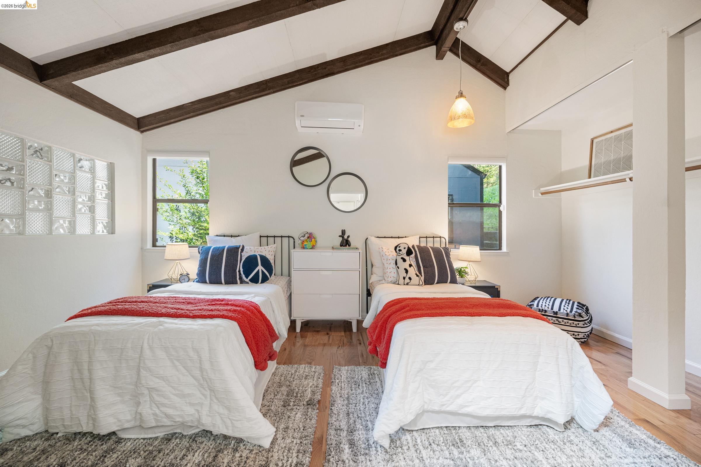 6600 Heather Ridge Way Oakland, CA 94611 - Photo 31 of 66 Vaulted ceiling featuring exposed dark wood beams, two windows, wood-finish flooring, and a glass block accent wall