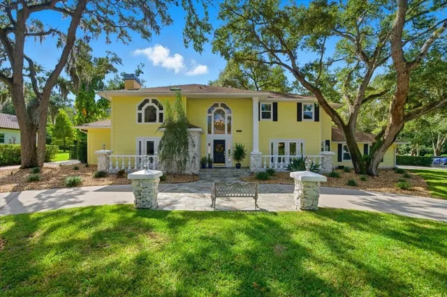 a front view of a house with garden and trees