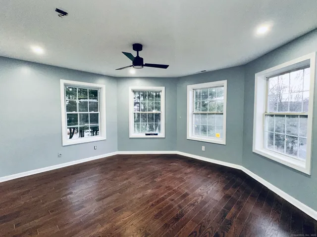 a view of an empty room with a window and wooden floor