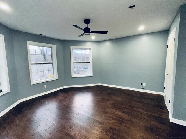 an empty room with wooden floor and windows