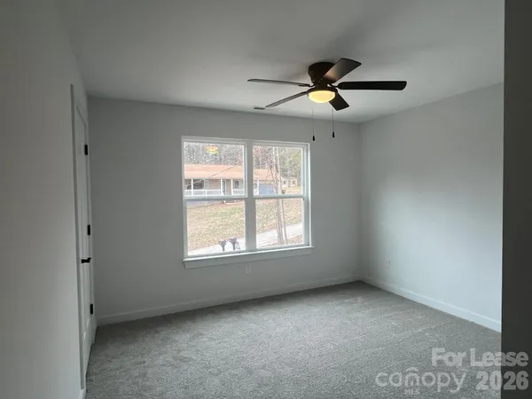 an empty room with windows and ceiling fan