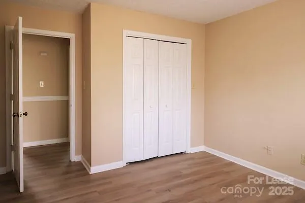 a view of an empty room with wooden floor and closet