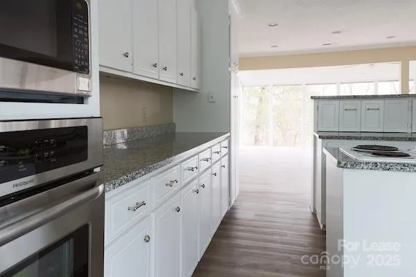 a kitchen with granite countertop a stove and a white cabinets
