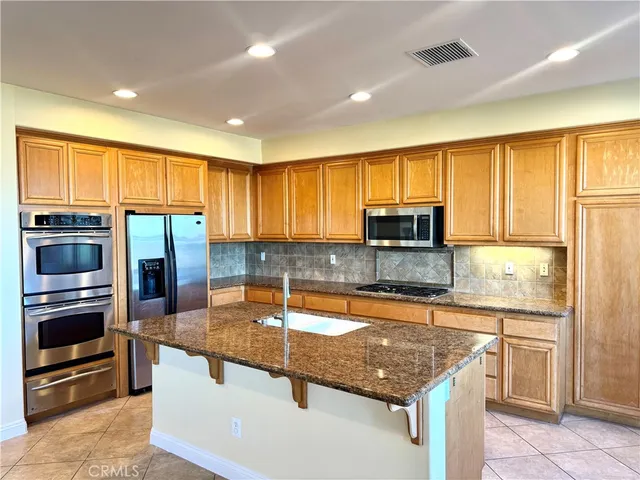 a kitchen with granite countertop a stove sink and refrigerator