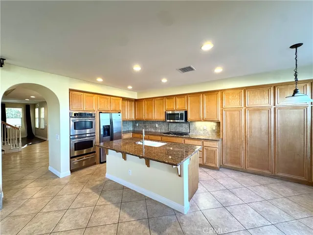 a kitchen with stainless steel appliances granite countertop a refrigerator a stove and a sink