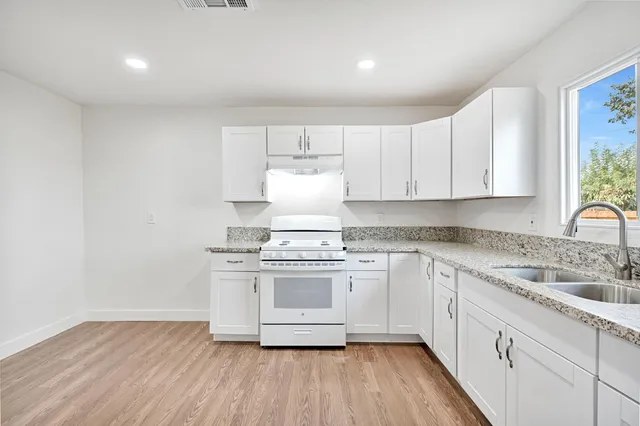 a kitchen with cabinets wooden floor and stainless steel appliances