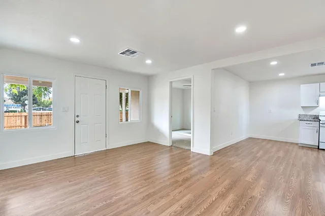 a view of empty room with wooden floor and window