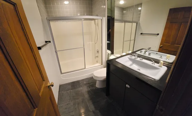 a bathroom with a sink a toilet a mirror and shower