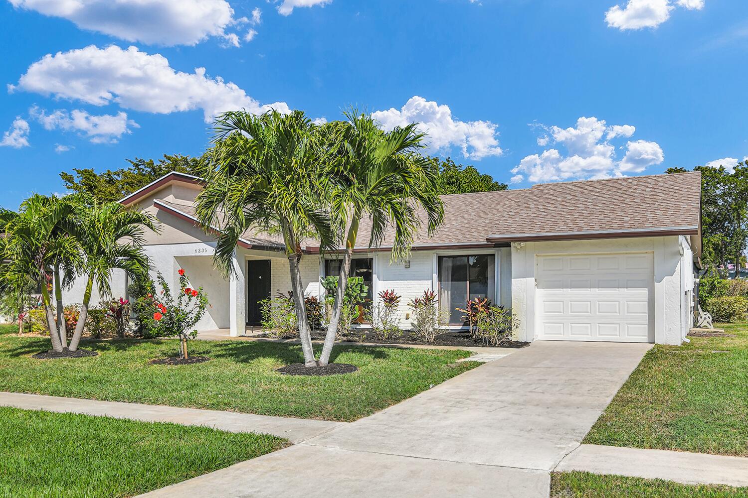a front view of a house with a yard and palm tree