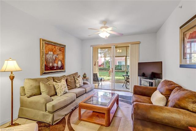 a living room with furniture a flat screen tv and a large window