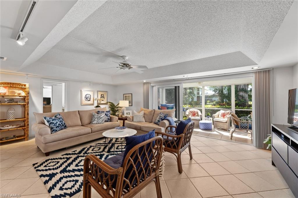 263 Candycane Lane, Unit 7 Naples, FL 34112 - Photo 15 of 50 a living room with furniture a flat screen tv and a floor to ceiling window
