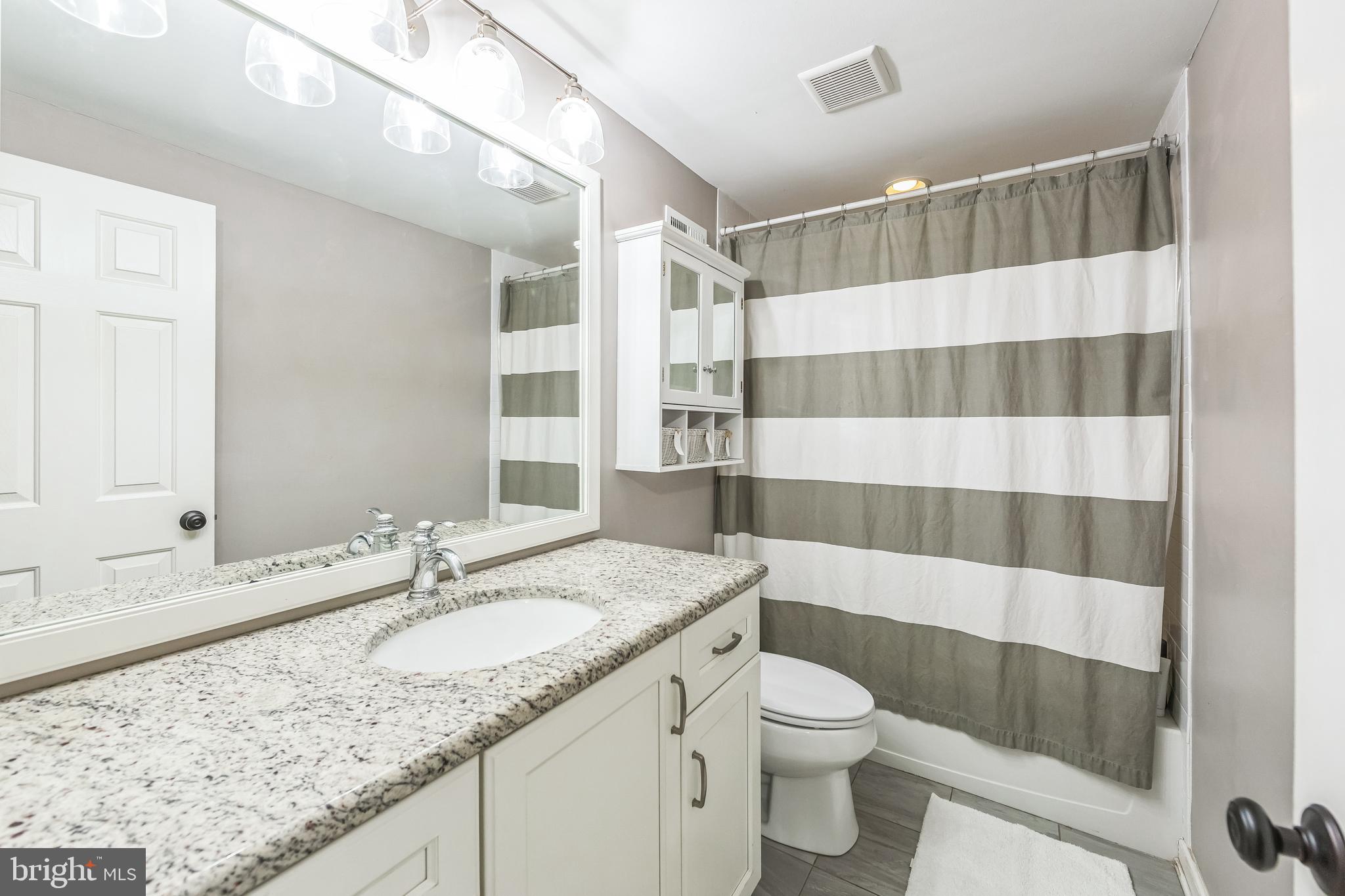 15 Oakford Road Wayne, PA 19087 - Photo 31 of 54 a bathroom with a granite countertop sink a toilet a mirror and shower