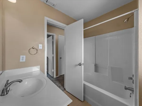 a bathroom with a tub shower vanity and a sink