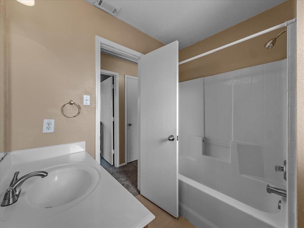 1119 Gaines Mills Road Grand Prairie, TX 75052 - Photo 15 of 29 a bathroom with a tub shower vanity and a sink