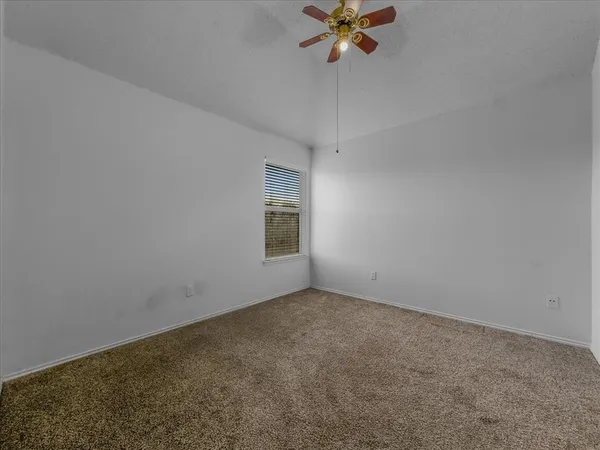 an empty room with a chandelier fan and windows
