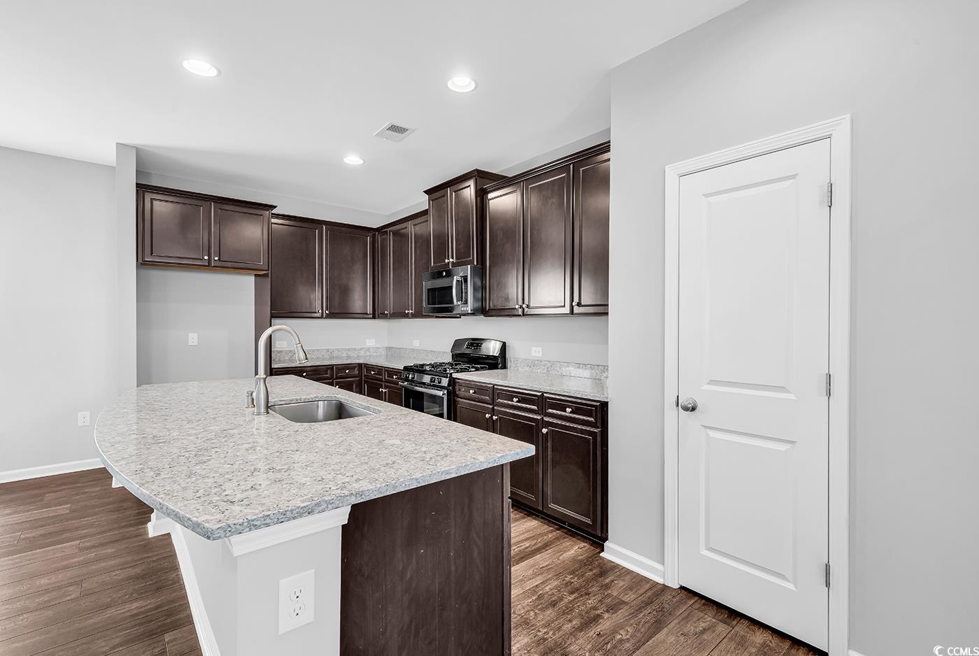 161 Splendor Circle Murrells Inlet, SC 29576 - Photo 7 of 37 Kitchen featuring dark brown cabinetry, appliances with stainless steel finishes, light stone countertops, dark wood-type flooring, and recessed lighting