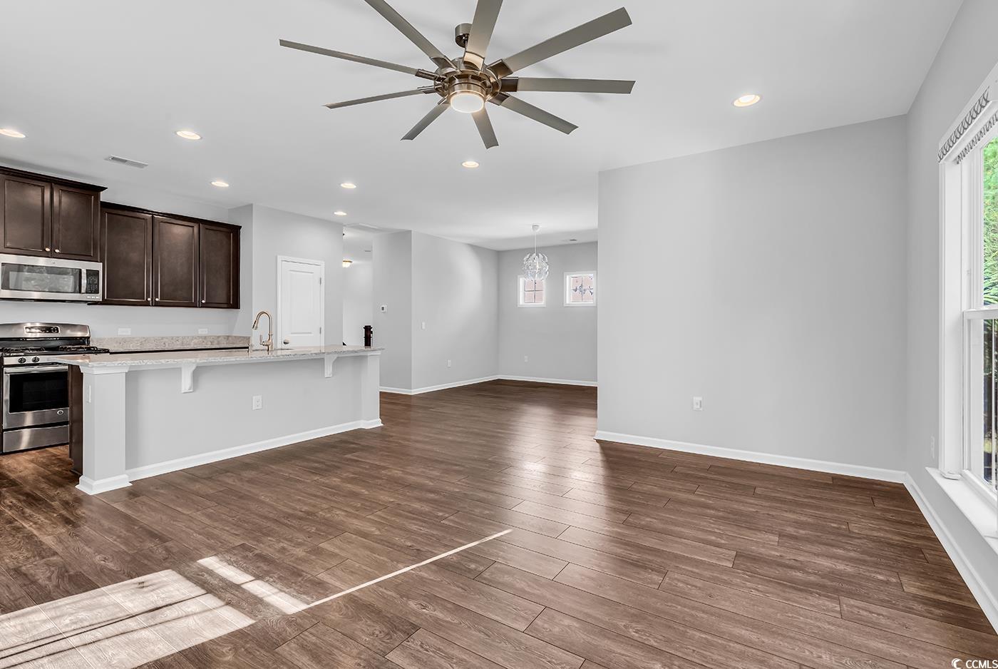 161 Splendor Circle Murrells Inlet, SC 29576 - Photo 10 of 37 Kitchen featuring appliances with stainless steel finishes, a kitchen bar, recessed lighting, dark brown cabinets, and light stone counters