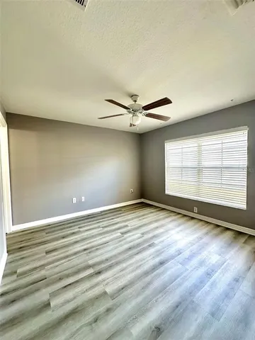 an empty room with wooden floor chandelier and windows