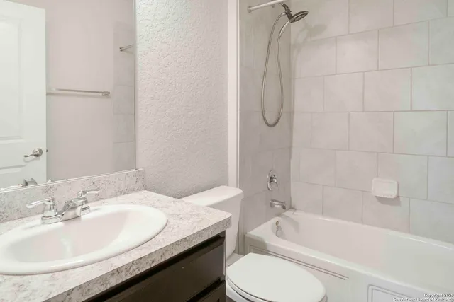 a bathroom with a granite countertop sink a toilet and bathtub