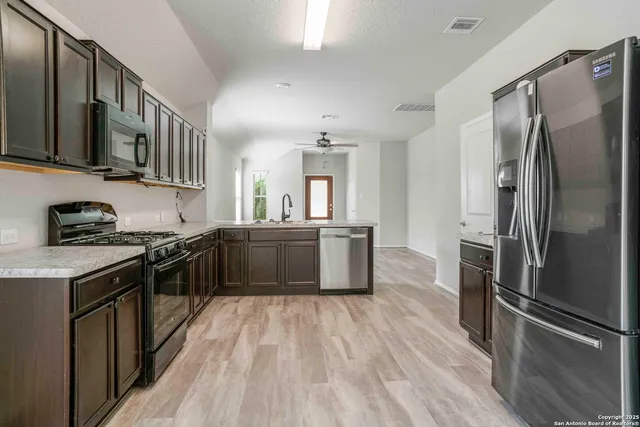 a kitchen with stainless steel appliances granite countertop a refrigerator a sink dishwasher a stove and a refrigerator