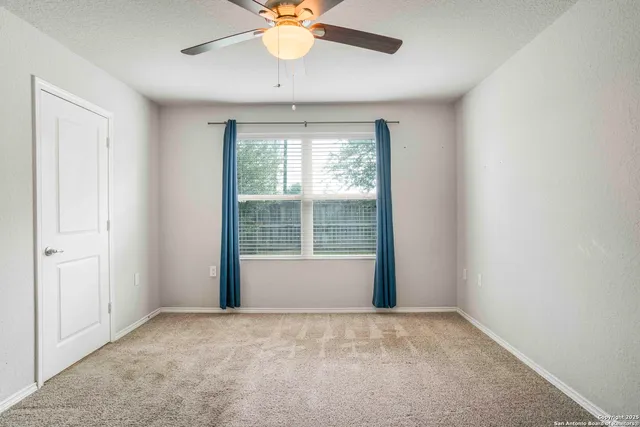 an empty room with a window and a ceiling fan