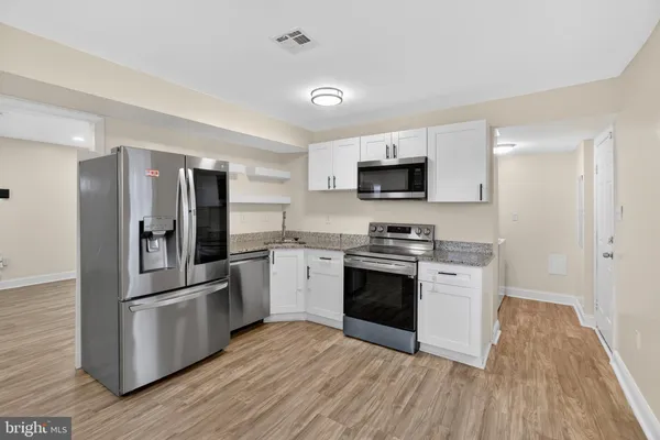 a kitchen with granite countertop a refrigerator and a stove top oven