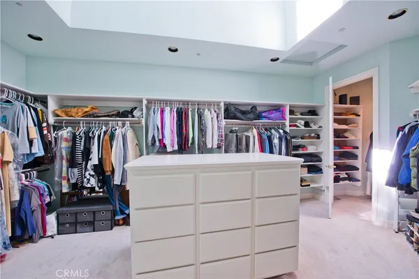 a view of walk in closet with clothes and shoes