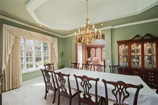 a view of a dining room with furniture a chandelier and large window
