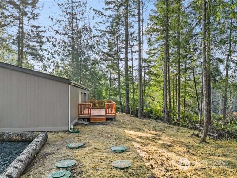 670 East Wilson Way Grapeview, WA 98546 - Photo 21 of 36 a backyard of a house with large trees and outdoor seating