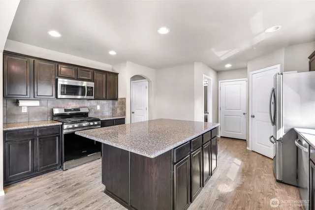 a dining hall with stainless steel appliances granite countertop a sink and dishwasher a stove with wooden floor