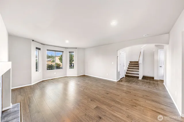 an empty room with wooden floor fireplace and windows