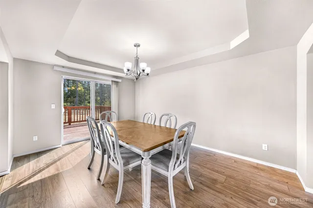 a kitchen with stainless steel appliances granite countertop a refrigerator a stove a sink a dining table and chairs with wooden floor