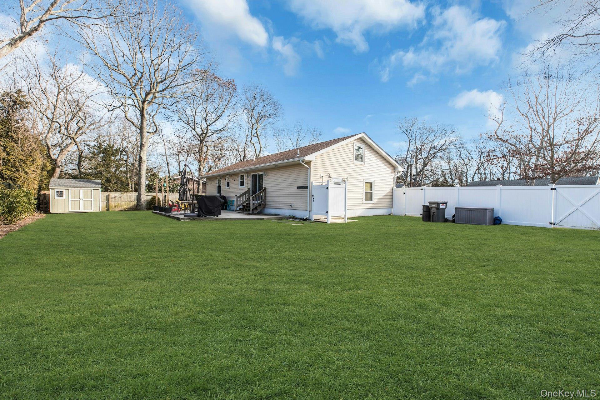 79 School Street Hampton Bays, NY 11946 - Photo 25 of 49 a view of a white house with a big yard with large trees