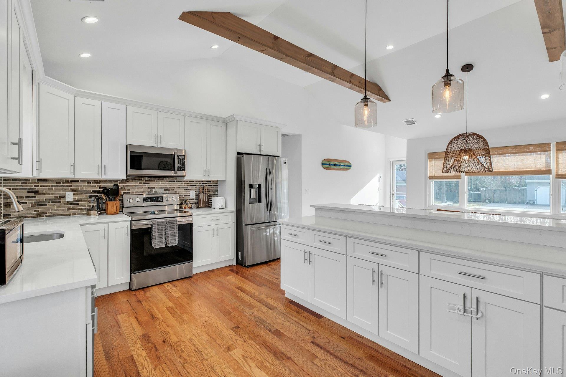 79 School Street Hampton Bays, NY 11946 - Photo 8 of 49 a kitchen with white cabinets stainless steel appliances and sink