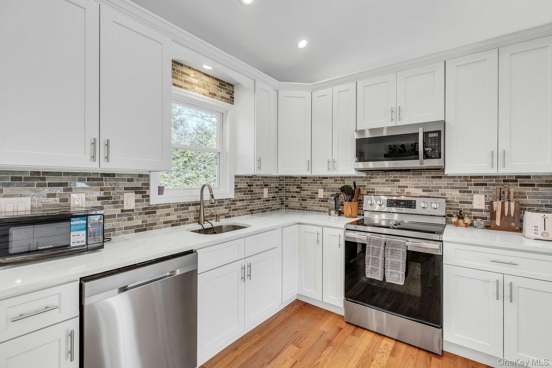 79 School Street Hampton Bays, NY 11946 - Photo 9 of 49 a kitchen with stainless steel appliances granite countertop a sink a stove a microwave and cabinets