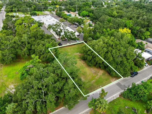 an aerial view of a residential houses with outdoor space and trees