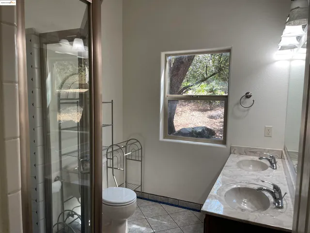 a bathroom with a granite countertop sink a toilet and a window