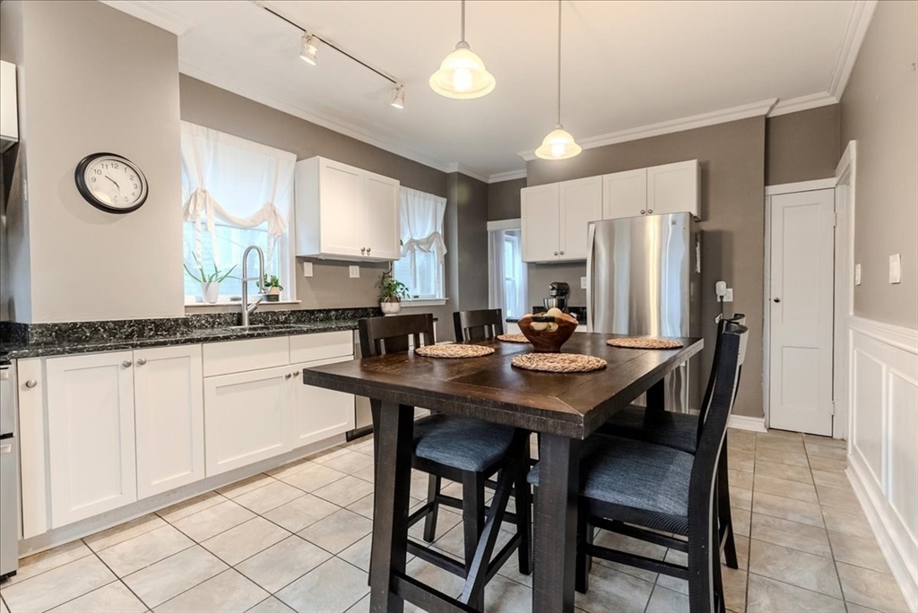 a kitchen with stainless steel appliances kitchen island granite countertop a dining table chairs and a sink