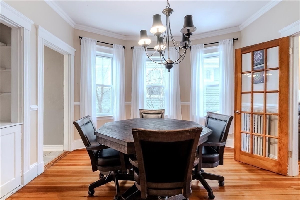 213 Reservoir Road, Unit 1 Brookline, MA 02467 - Photo 16 of 40 a dining room with wooden floor a chandelier a wooden table and chairs