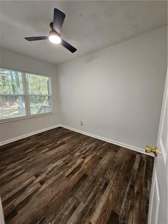 an empty room with wooden floor fan and windows