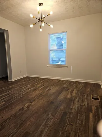 an empty room with wooden floor chandelier fan and windows